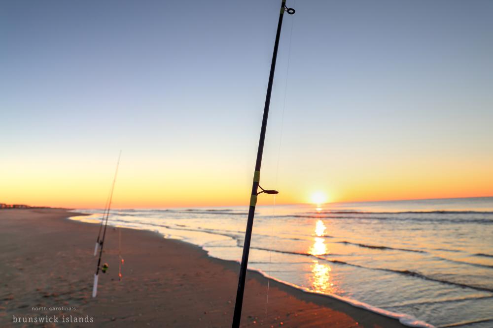 two fishing poles in the sand at sunrise