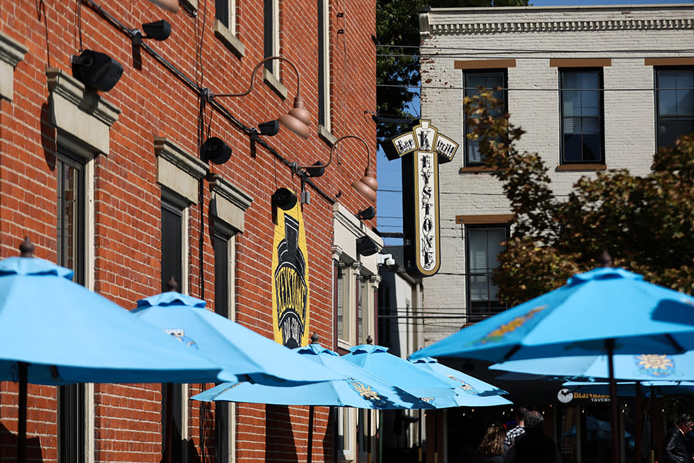 Blue umbrellas sit above patio tables at Keystone Bar & Grill, a red brick building