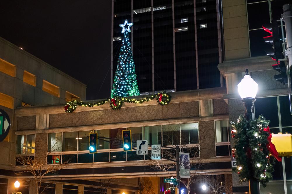 christmas tree on top of an enclosed skywalk at night in downtown fort wayne