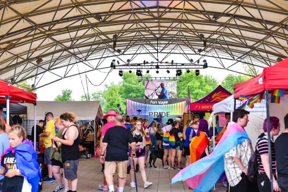 people with rainbow flags under a festival pavilion at pride fest in fort wayne
