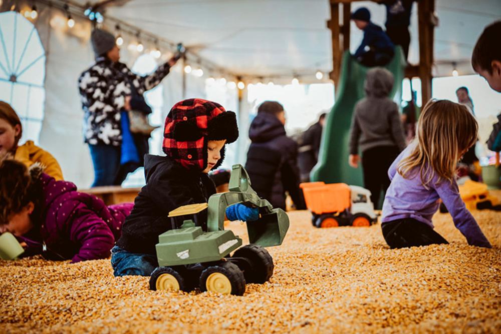 Children playing with toys in the corn sandbox at a fall festival