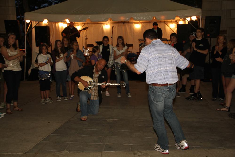 Man playing bouzouki and man greek dancing