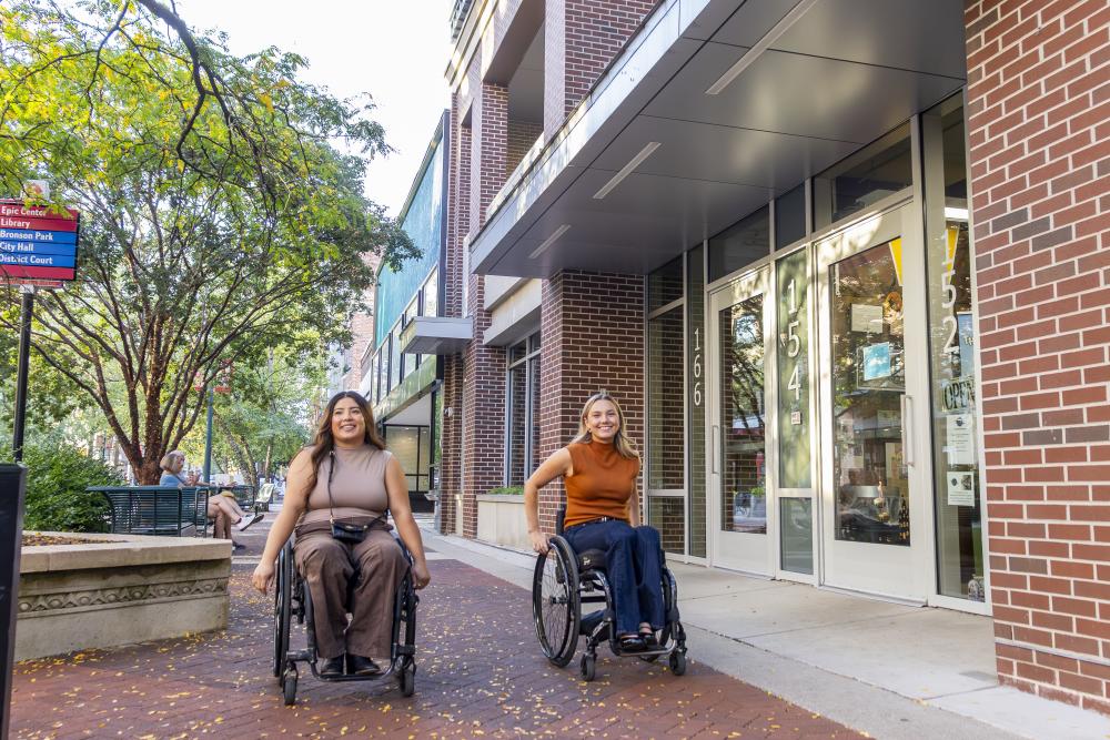 Two young women in wheelchairs roll on the Kalamazoo Mall.