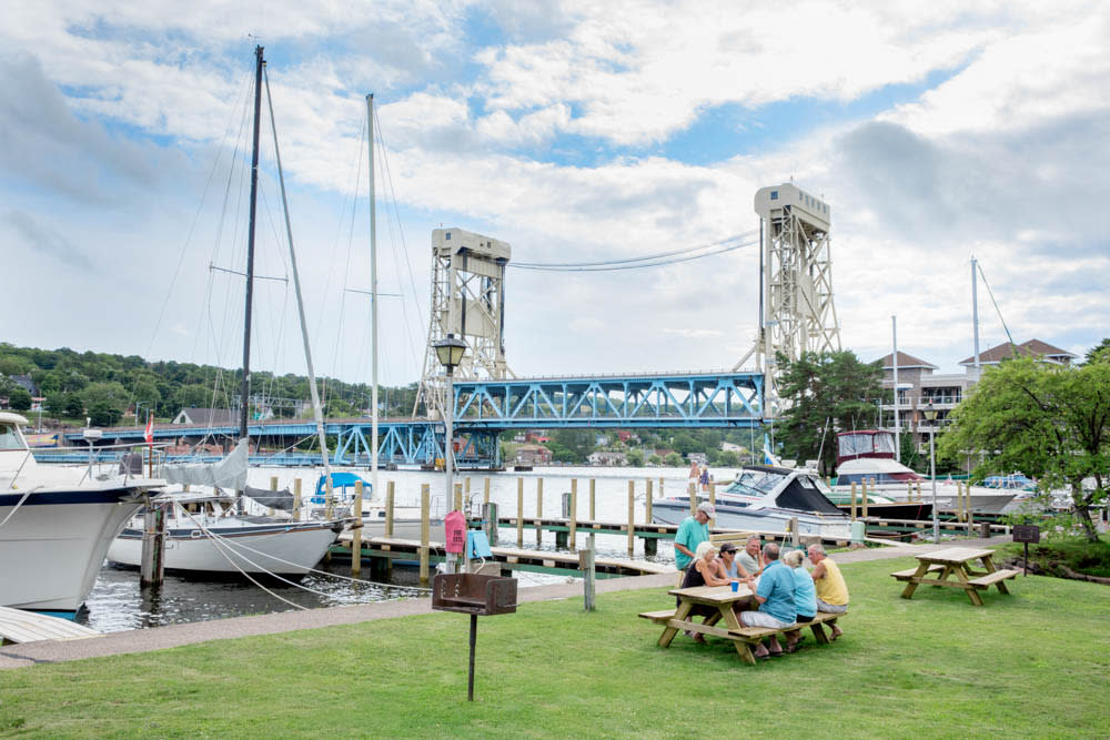 Boat marina with people at a picnic table with lift bridge in background