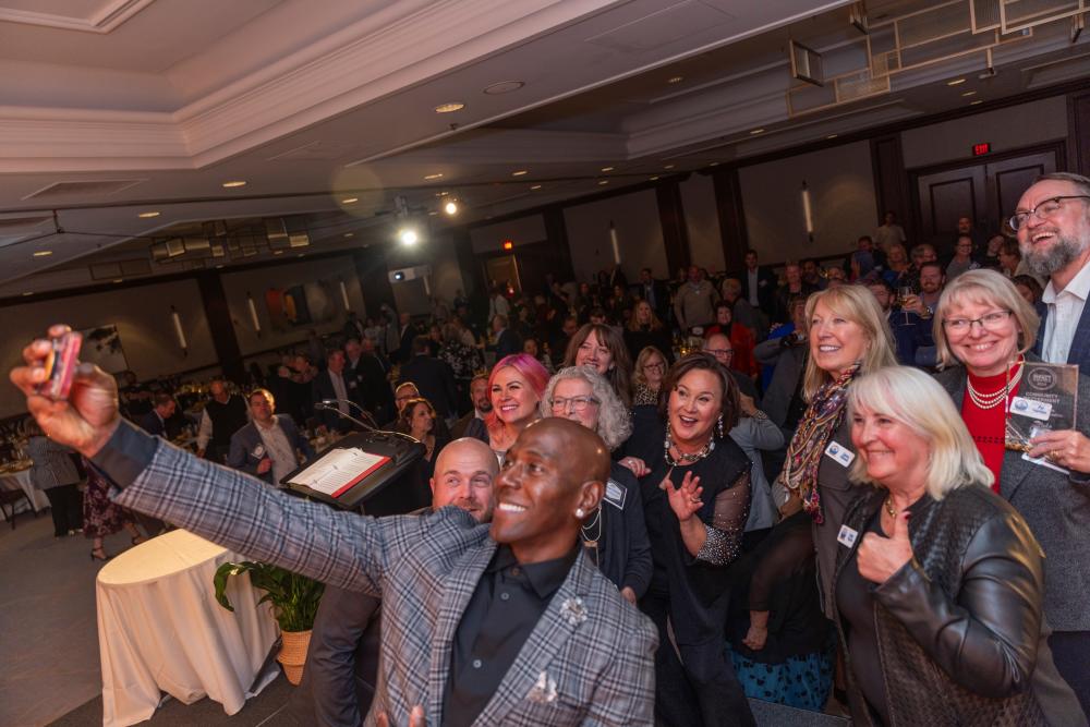 Picture of Donald Driver taking a selfie with attendees at the Annual Dinner