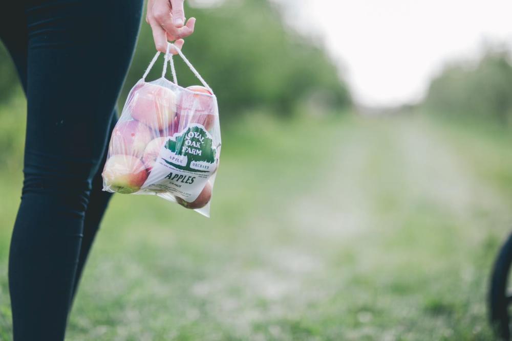 Person carrying a bag of apples at Royal Oaks Fram