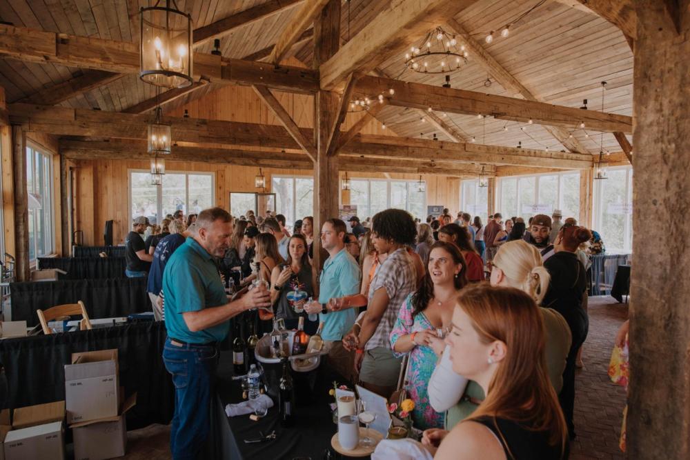 Guests sampling wine inside a timber barn at LoCo Wine Fest at Old Farm Winery at Hartland in Aldie, Virginia