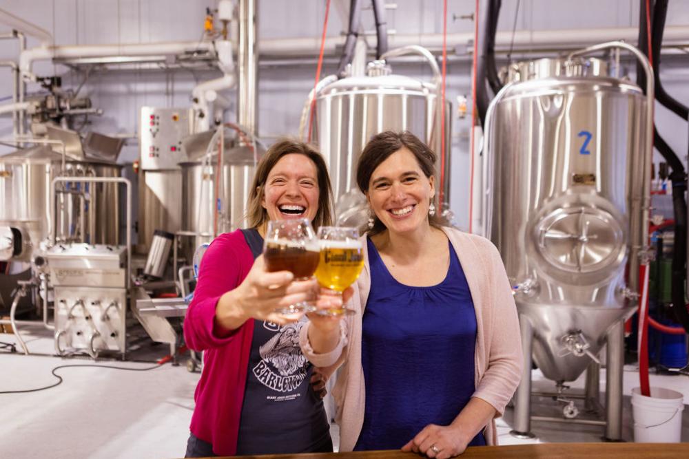 two women hold up beer at Giant JOnes Brewing