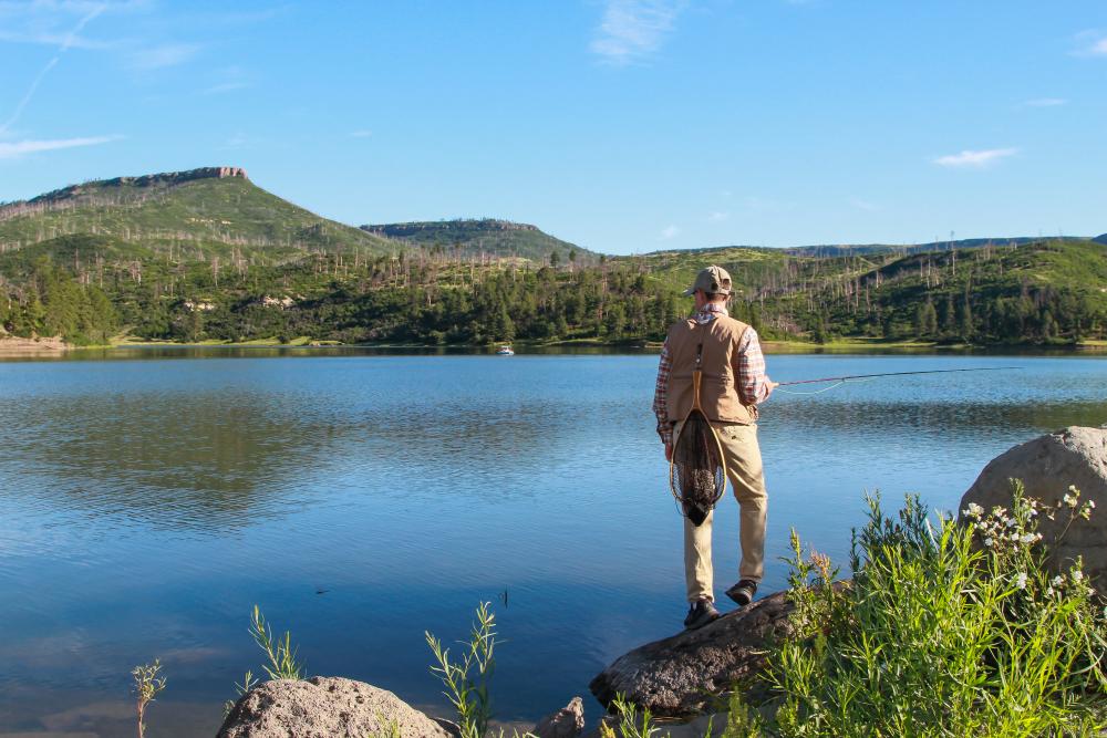 A fisherman stands at the edge of a lake at Sugarite Canyon State Park in Raton, New Mexico.