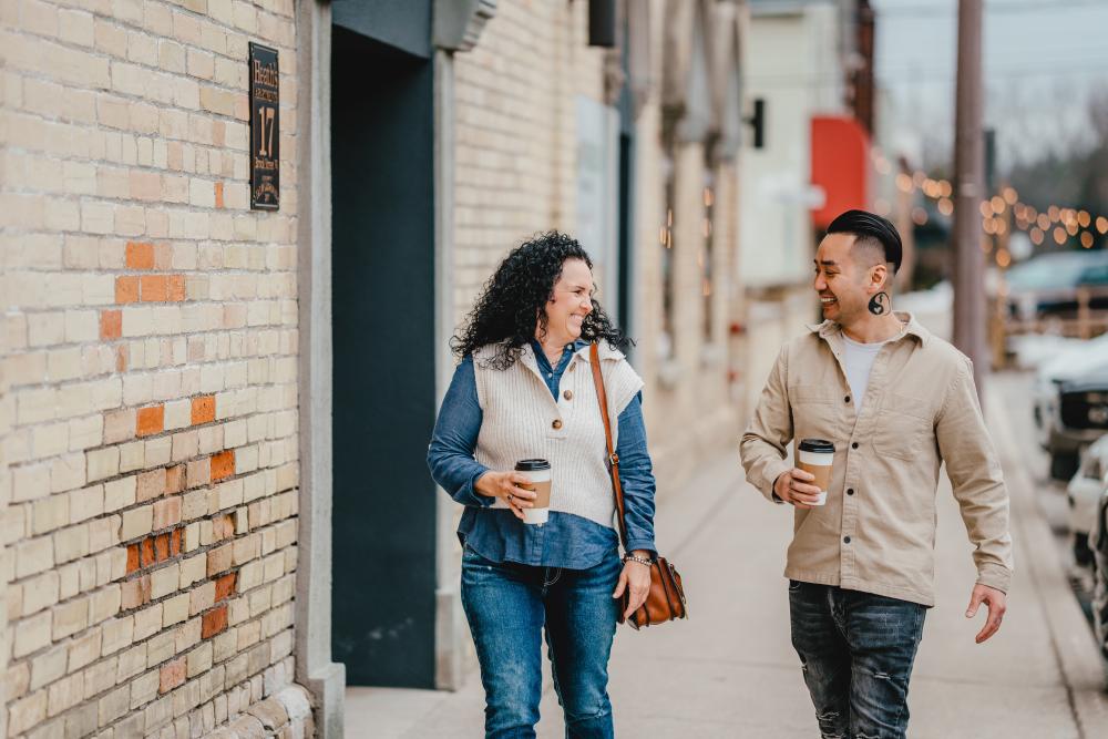 couple with coffee walking down a street