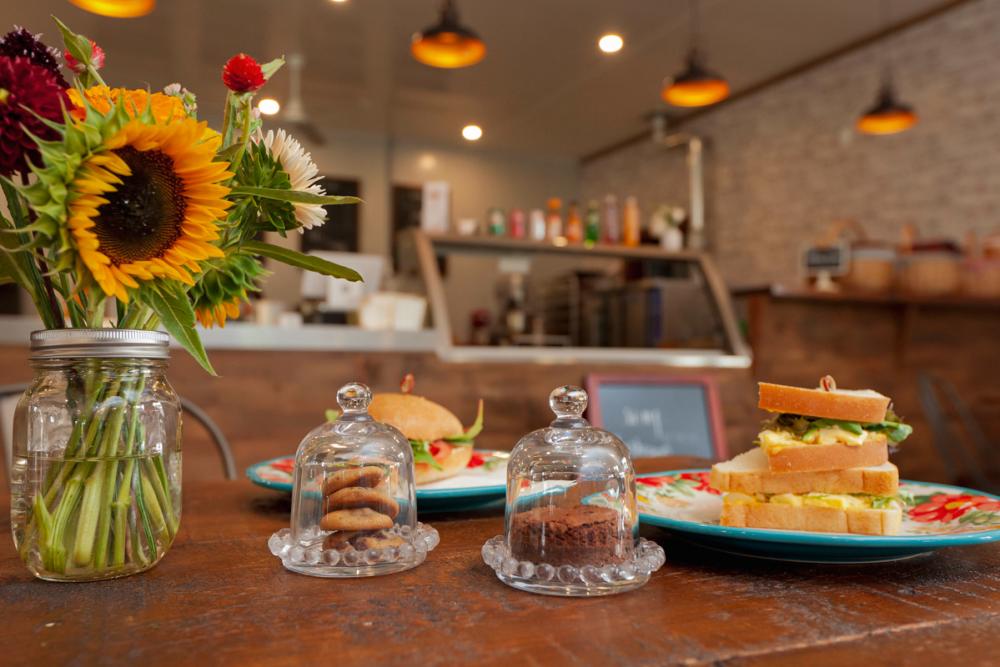 Bouquet of flowers on a table with baked goods and fresh sandwiches served on floral print plates