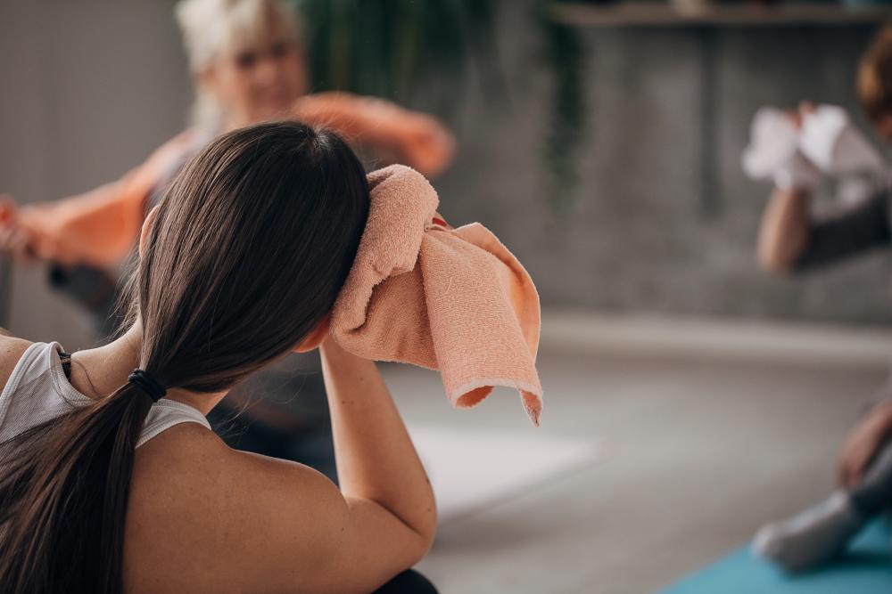 Lady with a towel doing hot yoga.
