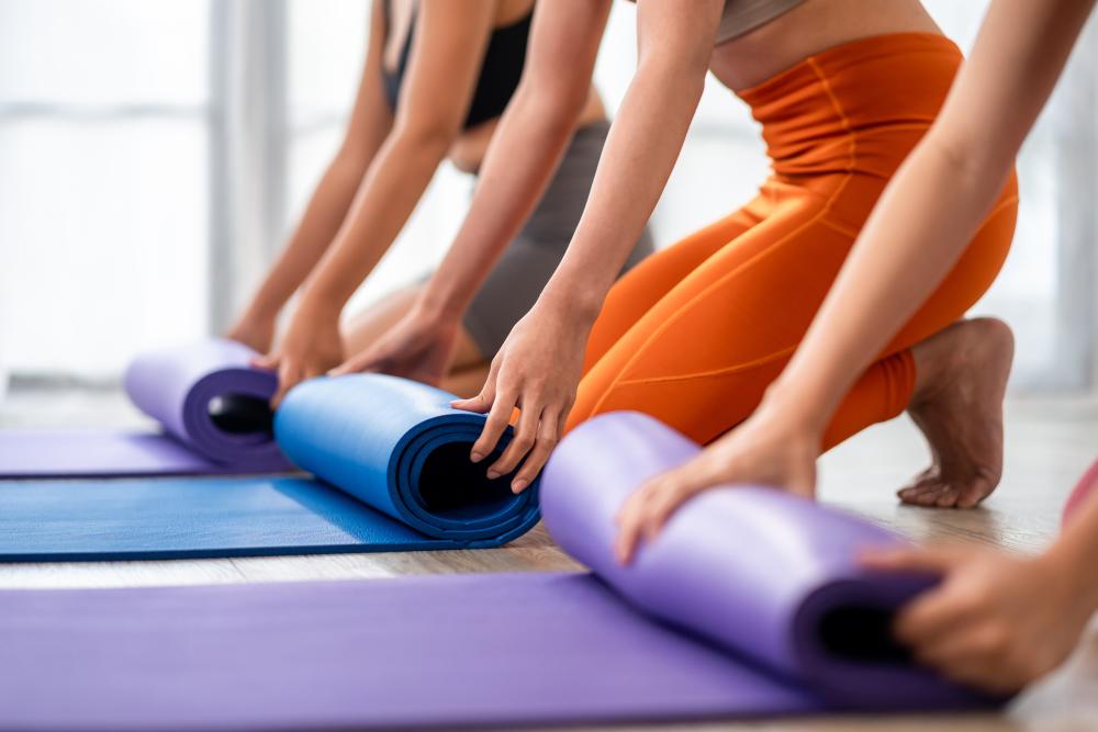 Three women rolling up yoga mats.