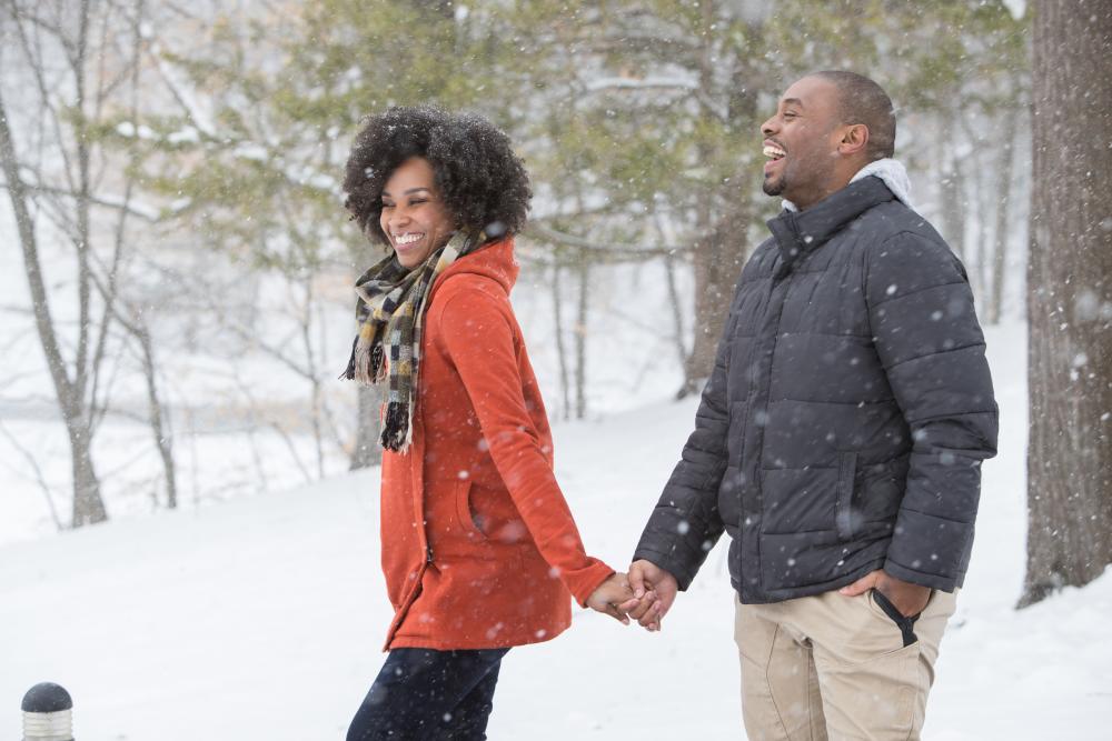 Couple smiling and enjoying the falling snow while on a walk