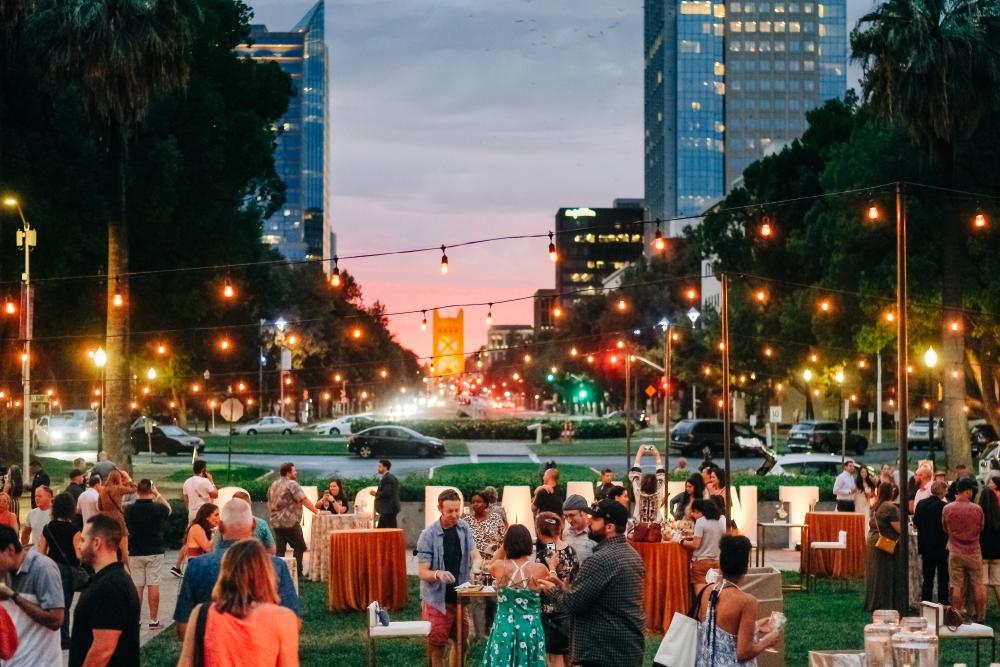 people outdoors at an evening wine event with the tower bridge in the background