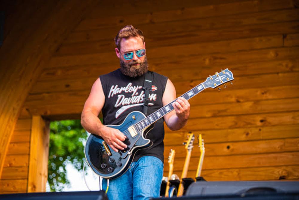 Man playing guitar on outdoor stage at festival.