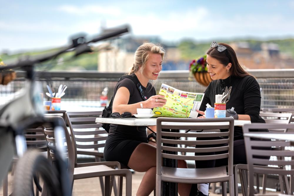 Two ladies Sitting outside Mamoosh in Newhaven looking at a map, with a bike in the foreground
