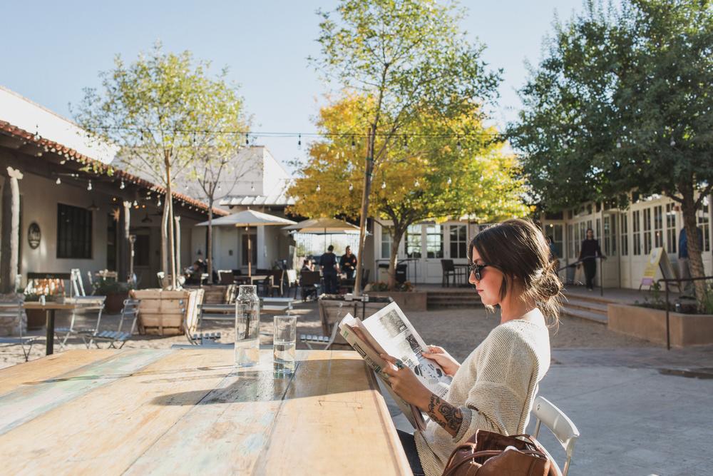 Woman Sitting at table reading a newspaper in the Mercado San Agustin