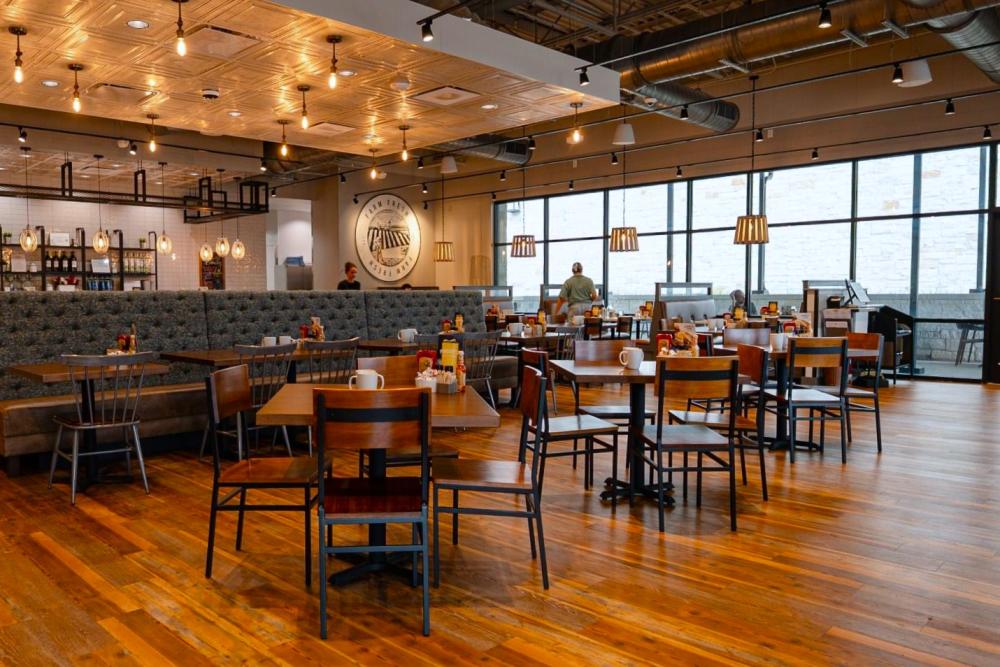 The First Watch dining room is modern but homey, featuring warm lighting, wood floors and tables, and plush booths.