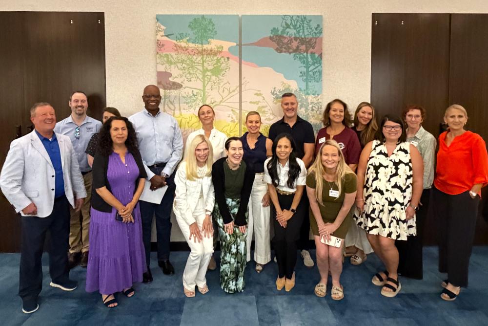 TWAC Board and Staff pose with The Art of Gratitude mural during its unveiling at the Kevin Brady Community Center.