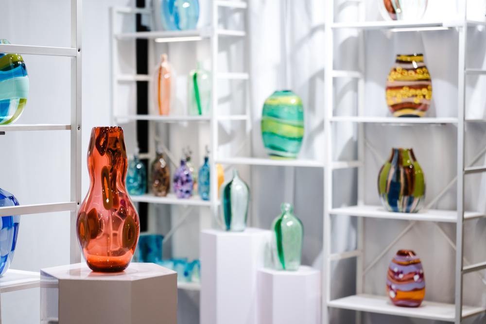 Artist Shara Funari's display of glass vases at the 2025 Texas Fine Craft Show. Her collection features pieces in all shapes and sizes, many in monochromatic or complimentary colors, many with spotted or striped patterns.