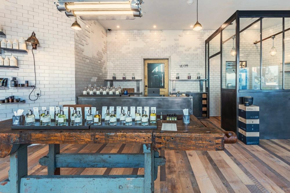 The interior of Le Labo at Market Street has a strong, industrial vibe with strategically broken tile walls, faded wood floors, canned lights, and rough wood tables set with dozens of Le Labo fragrances.