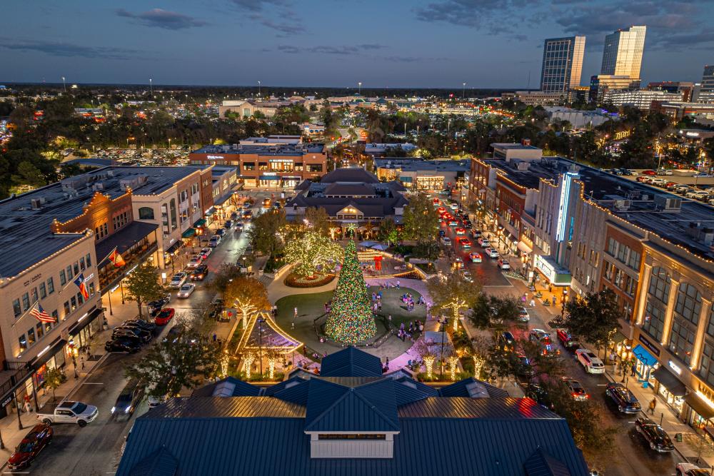 An aerial view of Market Street in Lights in The Woodlands, Texas. The camera hovers above Sixty Vines, facing the 70-foot Christmas tree in Central Park and The Woodlands Towers.