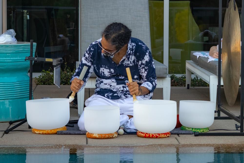A man in a tropical-style clothes plays singing quartz bowls beside the rooftop infinity pool at The Westin at The Woodlands.