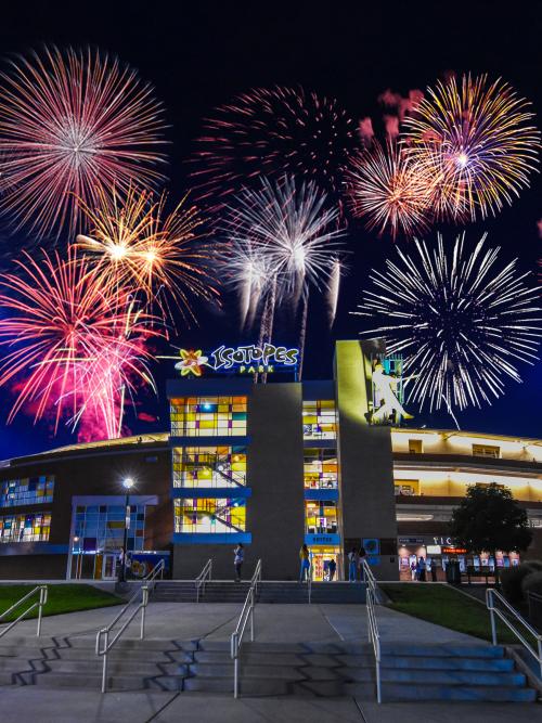 A shot of Isotopes Park in the dark with fireworks exploding overhead.