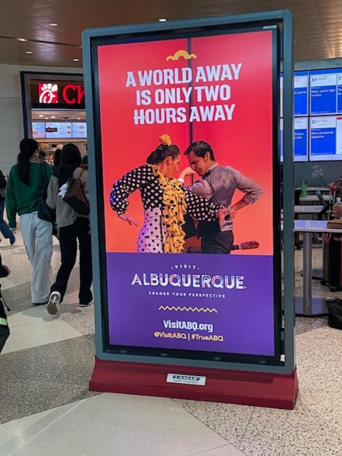A picture showing a Visit Albuquerque ad on a board in Dallas Love Field airport.