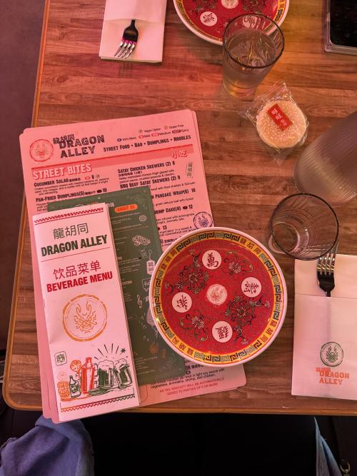 Table setting at Dragon Alley in Huntsville featuring colorful plates, menus, drinks, and branded details.