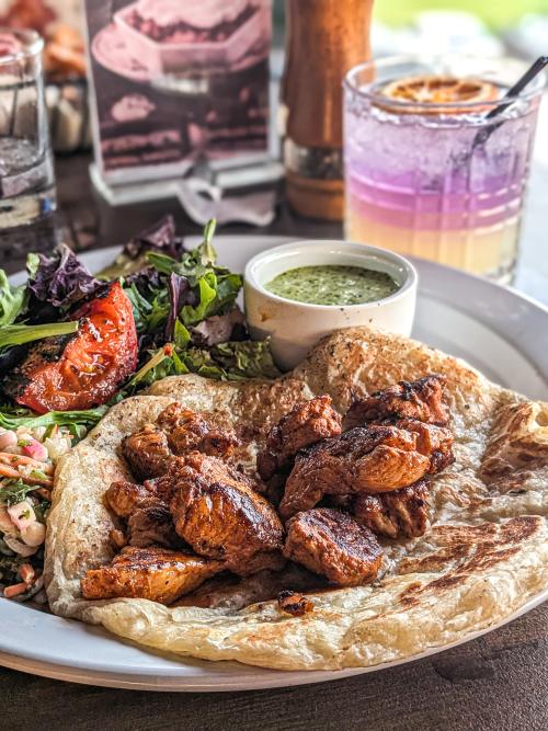 Grilled chicken served over warm flatbread with a side salad and dipping sauce at Prohibition Rooftop Bar & Grill.
