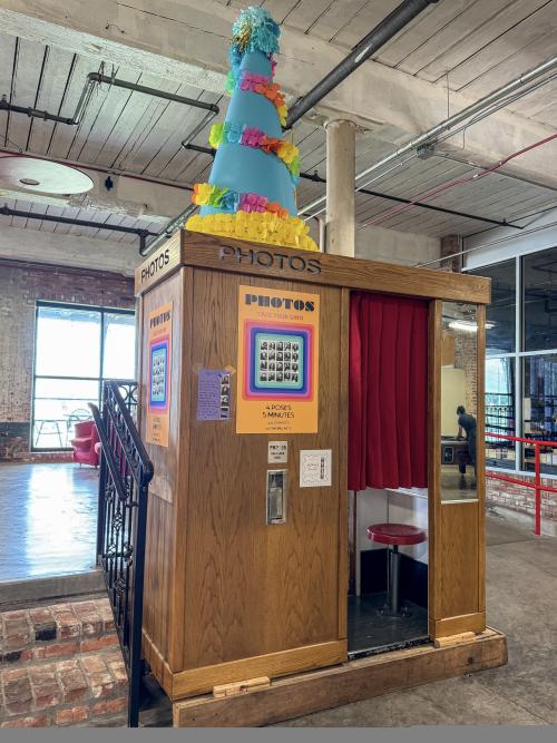 Vintage wooden photo booth with a red curtain and colorful decorations inside Lowe Mill ARTS & Entertainment in Huntsville.