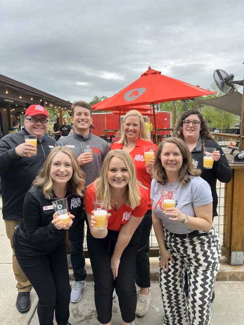 Visit Athens staff pose for a picture with glasses of Wide Open IPA in front of a red umbrella
