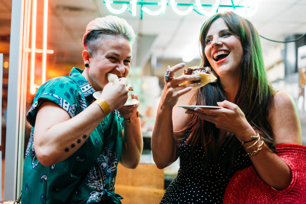 two women biting into tacos at Hot Luck Live Food and Music Festival in austin texas