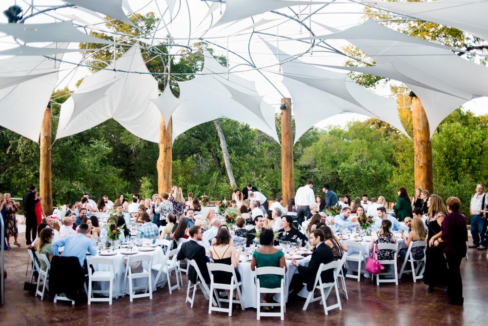 Guests of event at round banquet tables under the white geometric canopy at Cypress Valley.