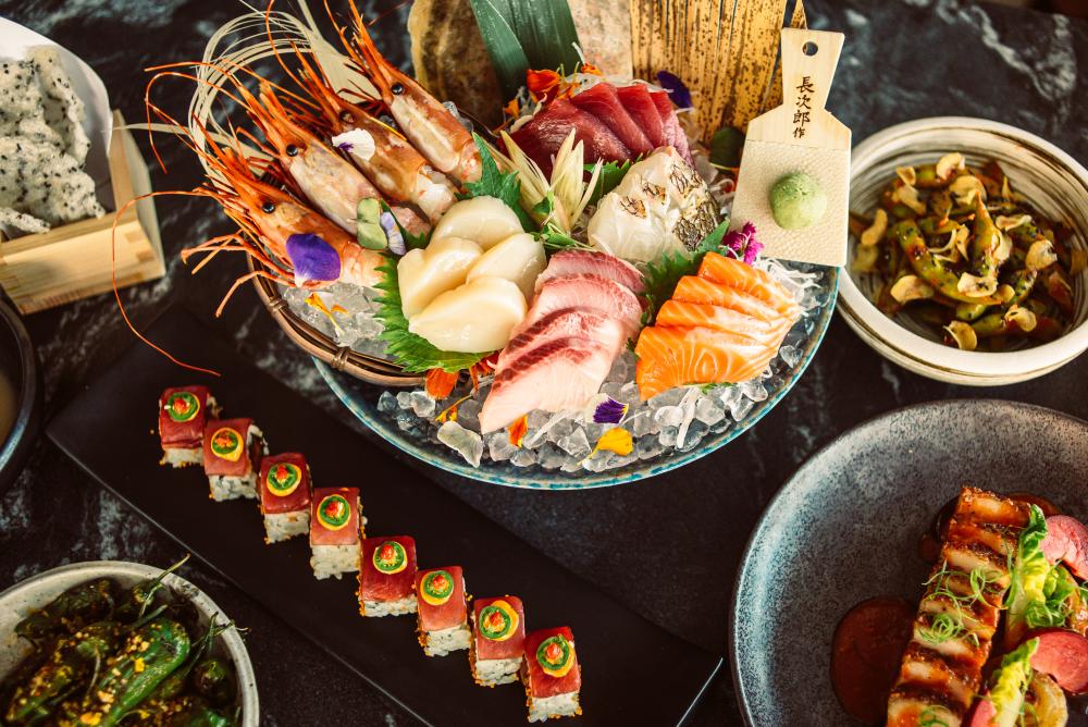 Colorful sashimi slices arranged delicately on a bowl of ice, surrounded by sushi rolls.
