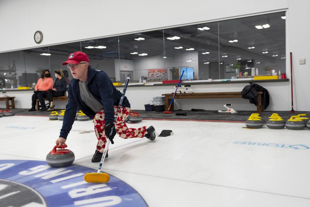 Fort Wayne Curling Club co-founder Craig Fischer demonstrates how to slide and curl the stone