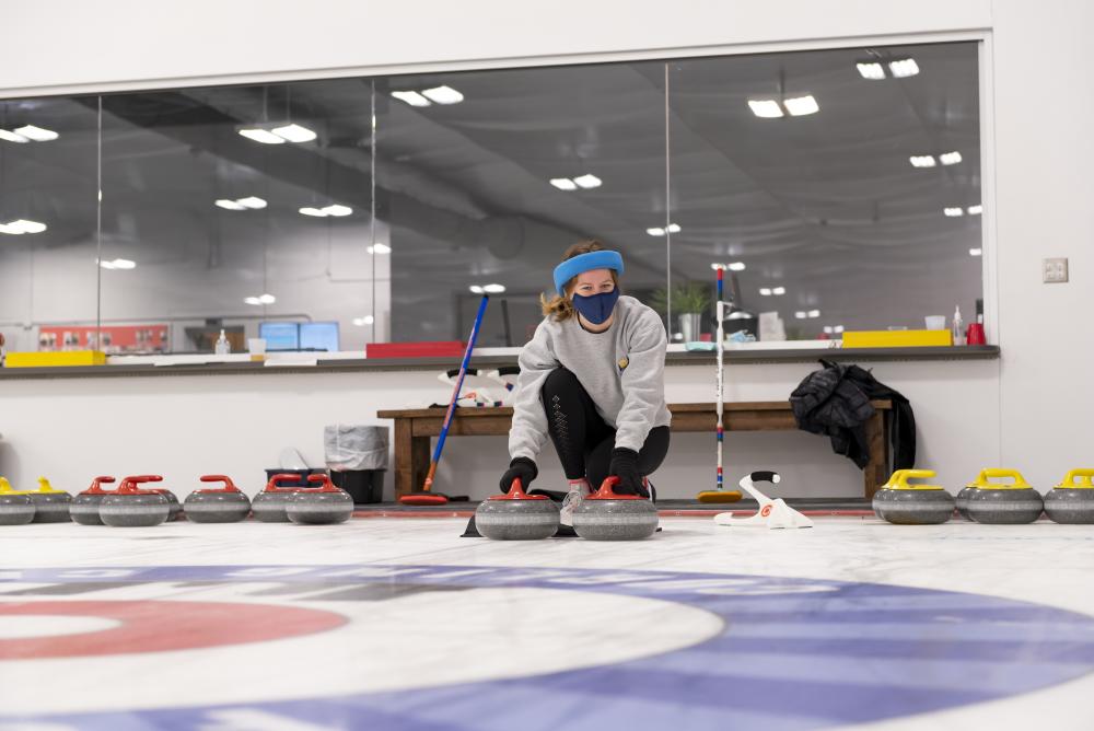 Girl preparing to slide a stone on the ice at the Fort Wayne Curling Club