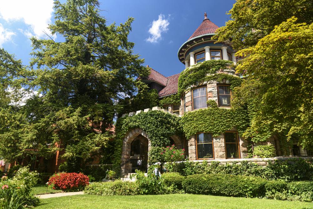 exterior of a cobblestone house covered in ivy with a yard with grass in front