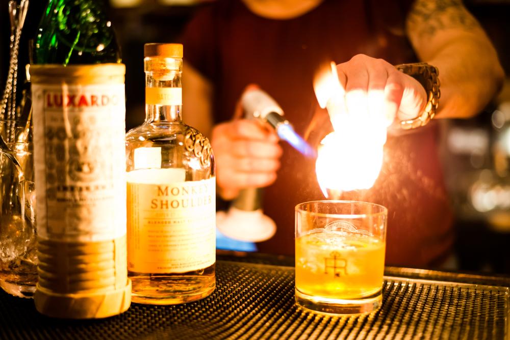 Maleah Christie, a co-owner, making a drink at the speakeasy-style bar using a blowtorch, Revival 1869, in Clayton, NC.