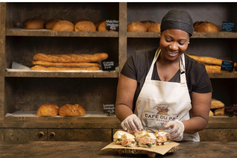 Smiling chef prepares a sandwich in Cafe du Pain