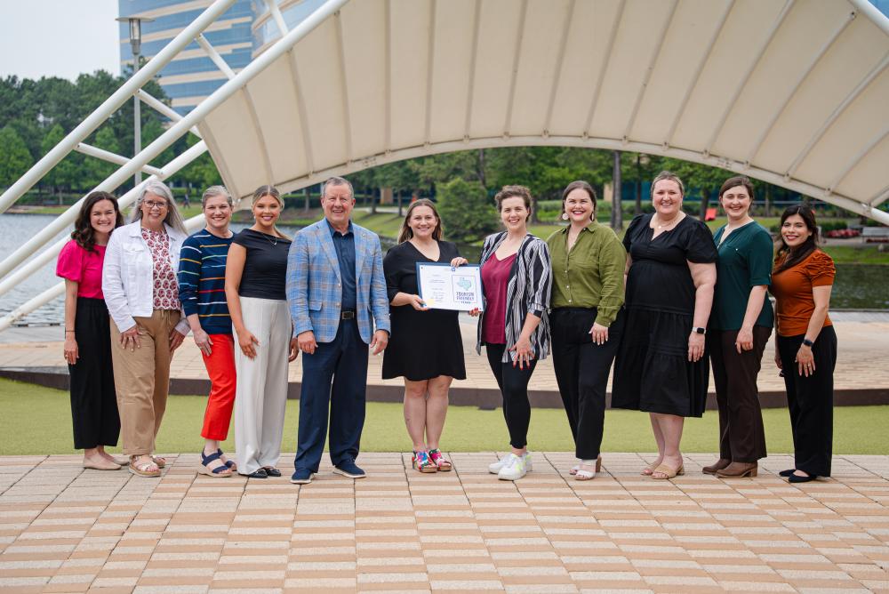 Visit The Woodlands accepts the Tourism Friendly Certification for The Woodlands Township. From left: Andrea Day, Julie Quinn, Ashley Fenner, Brooklyn Newell, Nick Wolda, Amber Parsley, a representative from the Governor's Office, Elizabeth Eddins, Vargo Williams, Rachael Varner, and Carla Twidell.