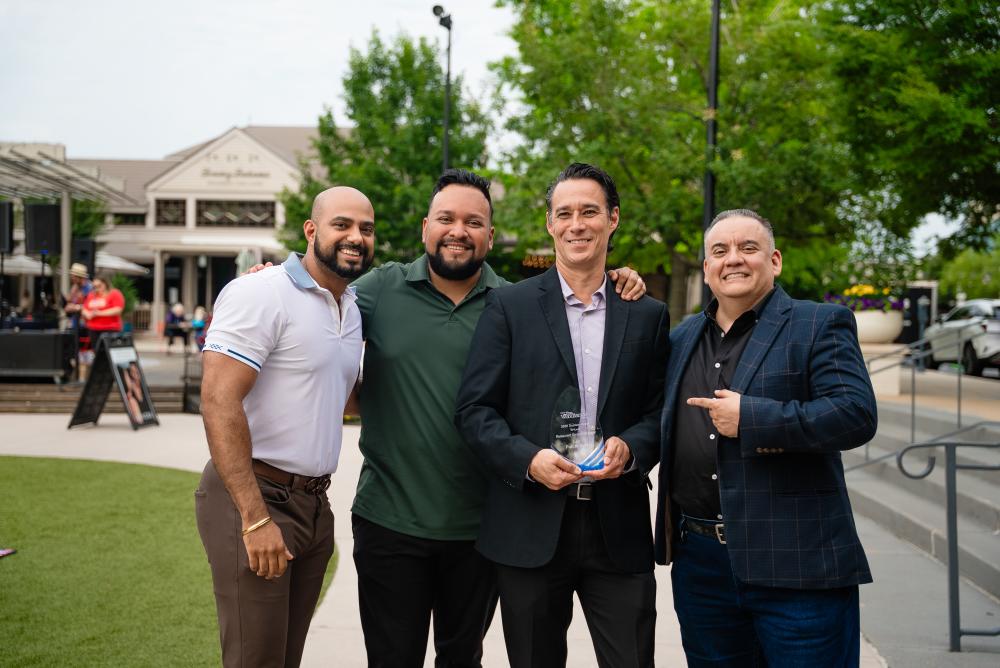 For National Travel and Tourism Week, a winner of Visit The Woodlands' hospitality awards poses with his team from Amrina. The team is four men: two in sports shirts and slacks, two in business suits.