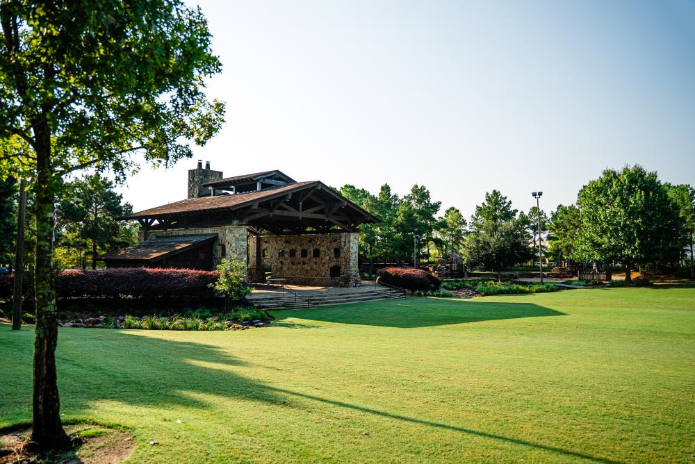 The Lodge at Rob Fleming Park sits on a well-kept lawn surrounded by purple bushes and bright green trees.