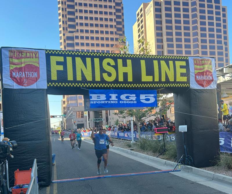 Participants celebrate as they cross the finish line of the 2023 Duke City Marathon.