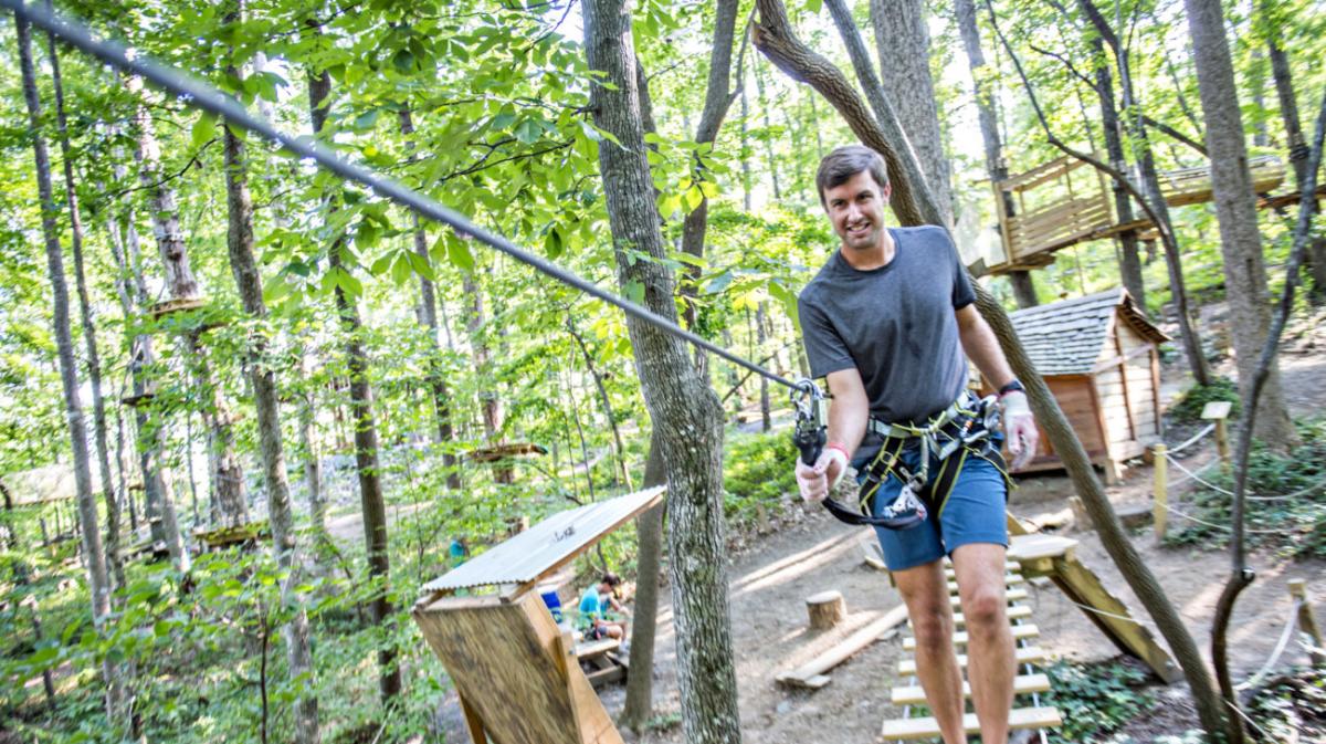 man walking across bridge through trees