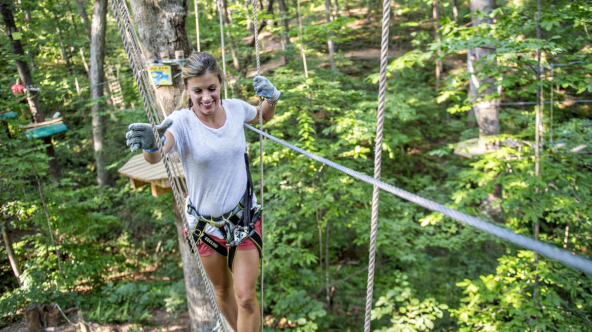 woman walking on safely line through trees