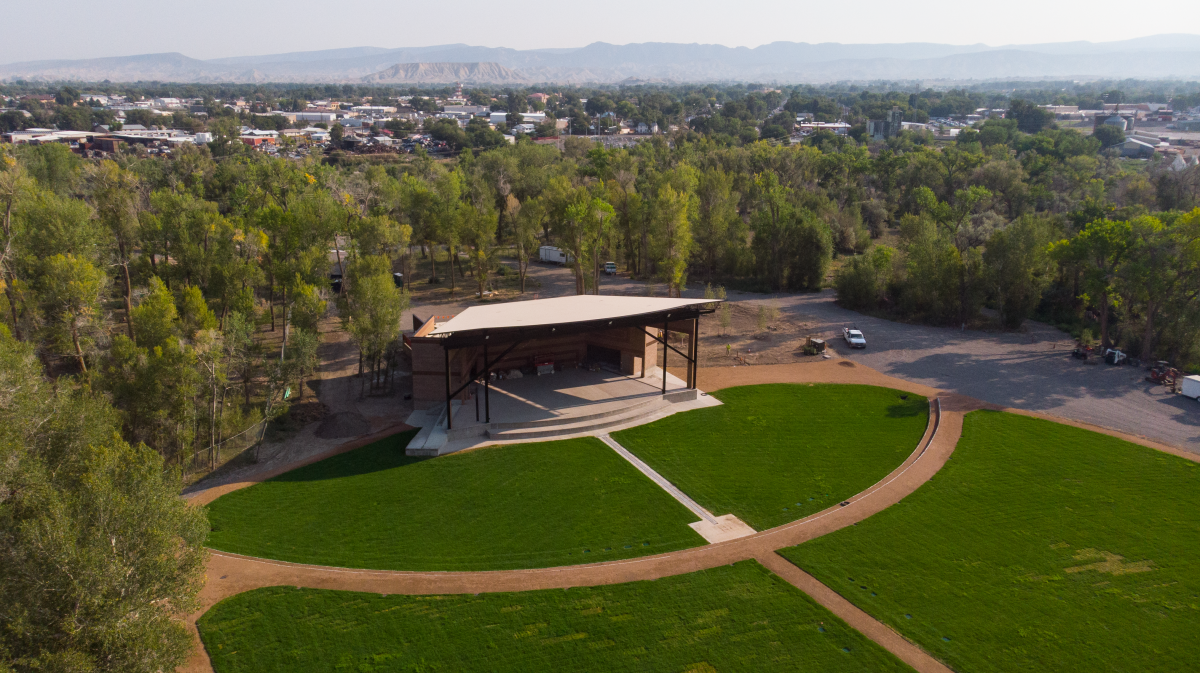 Drone photo of the completed Montrose Rotary Amphitheater and its green grounds with the City of Montrose and the Gunnison Gorge in the distance.