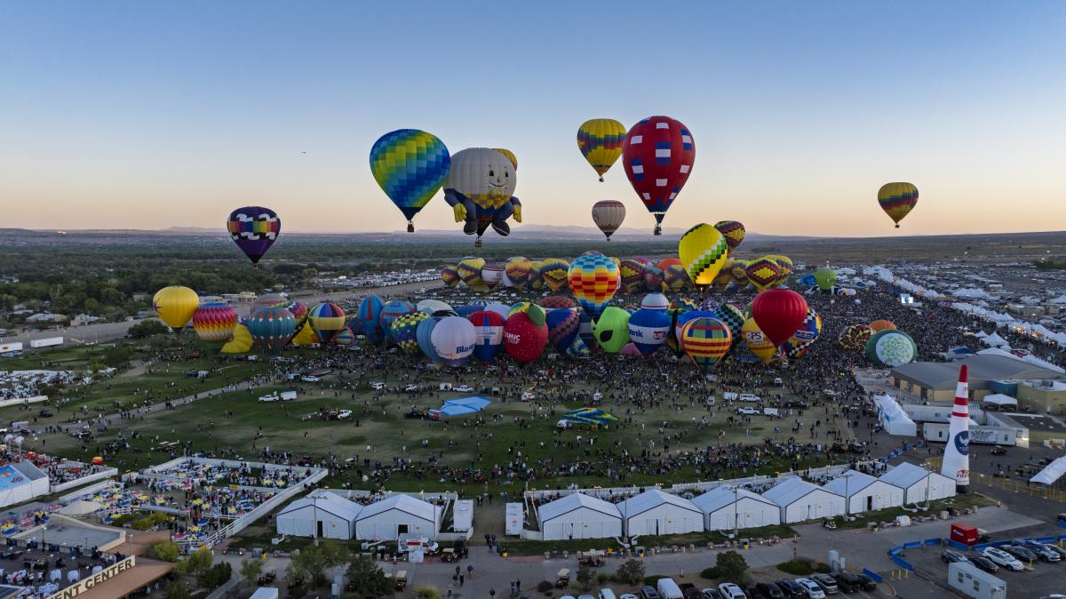 Dozens of hot air balloons take off at dawn during a mass ascension at Balloon Fiesta.